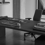 Minimalist grey design studio desk. Blueprint and tools for architecture on left; fabric swatches and vase for decor on right. Bicolor.