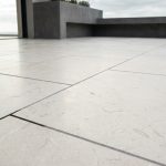 Terrasse moderne en dalles de pierre de Comblanchien beige clair avec joints gris soulignant le calage régulier.